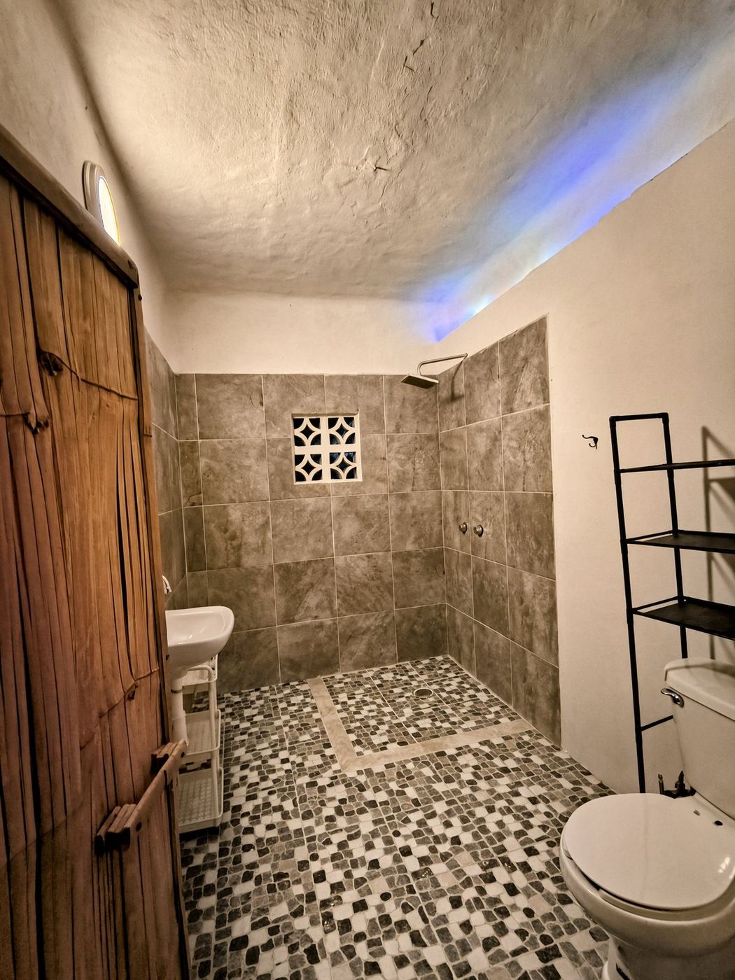 A bath at La Casa Grande, bamboo door, stone tile, and a mosaic floor