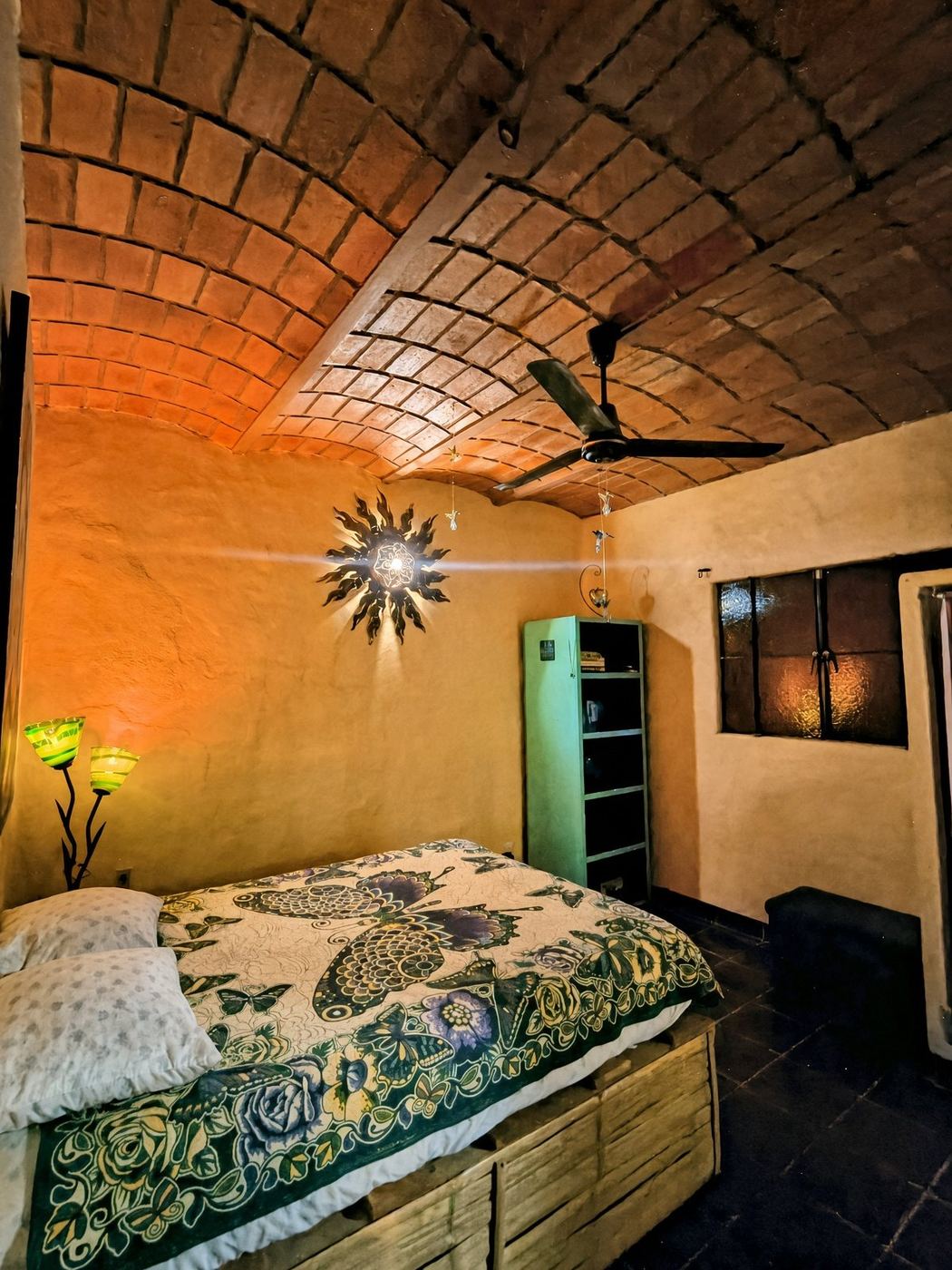A bedroom at La Casa Grande, butterfly quilt under a brick vault and a sunburst lamp
