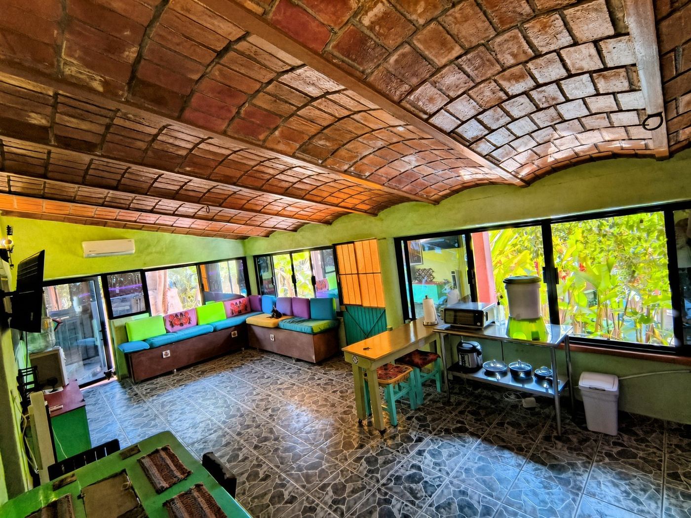 La Casa Grande’s long room, a brick vault, bright cushions, and the banana garden through the windows