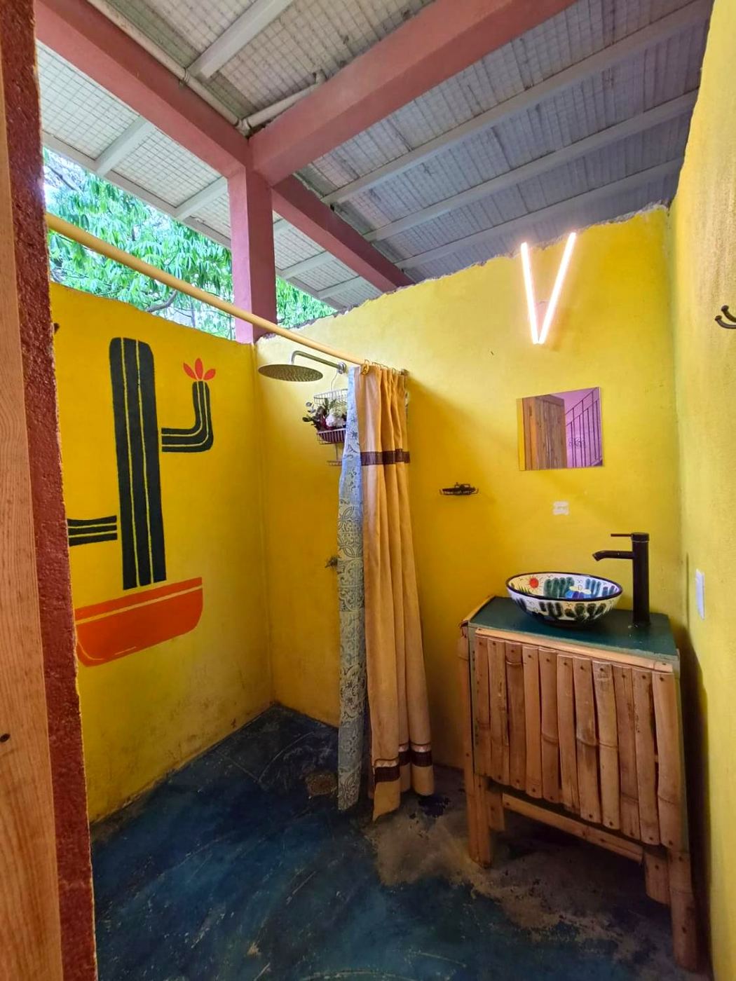 The open shower at Two bedroom Delight, a painted cactus on a yellow wall
